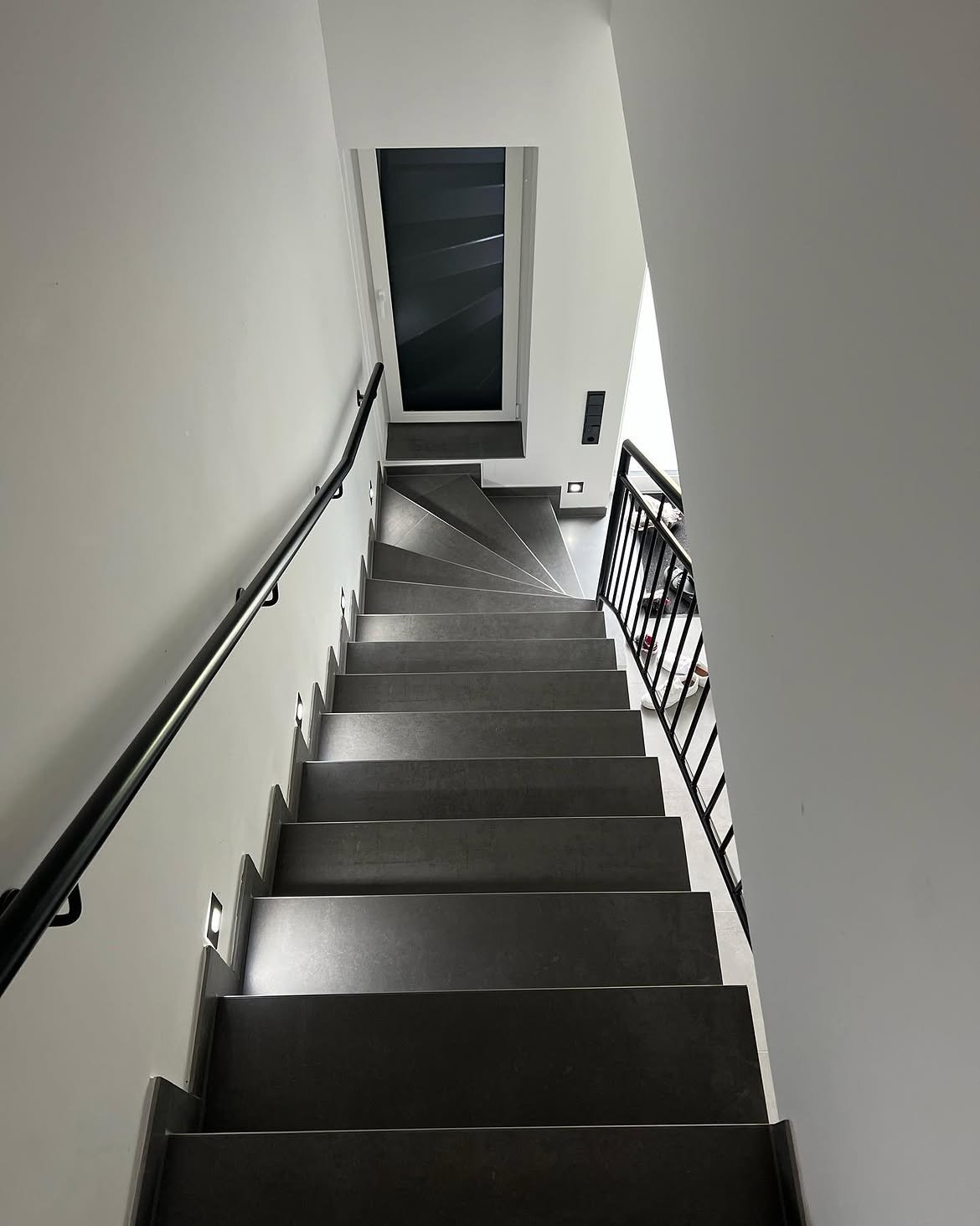 Geflieste Treppe mit anthrazitfarbenen Trittstufen aus Feinsteinzeug, ausgeführt von Fliesen-IKT